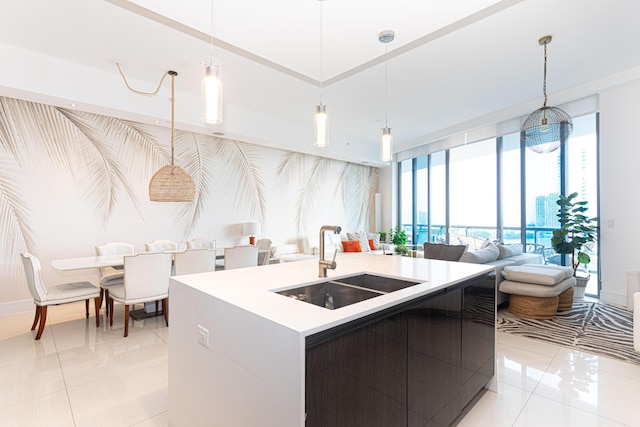 kitchen with open floor plan, light countertops, decorative light fixtures, an island with sink, and a sink