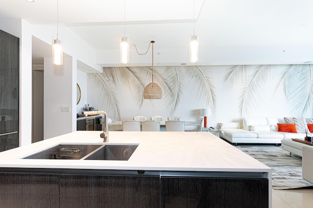 kitchen with a sink, open floor plan, decorative light fixtures, and a center island with sink