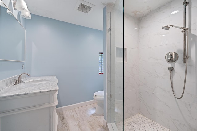 bathroom featuring hardwood / wood-style floors, vanity, toilet, and a tile shower