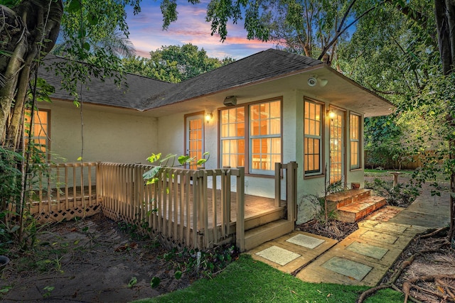 back house at dusk featuring a deck