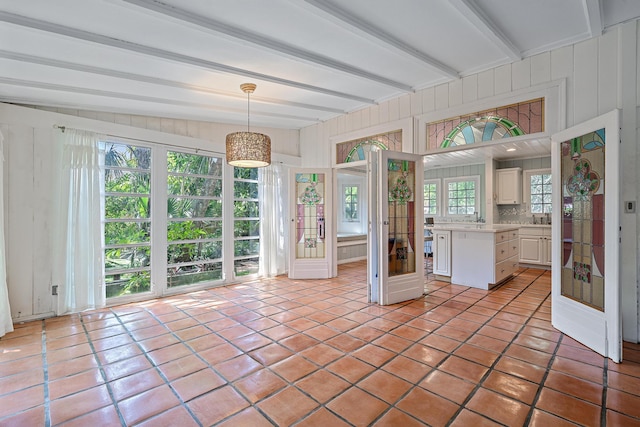 sunroom / solarium featuring vaulted ceiling with beams