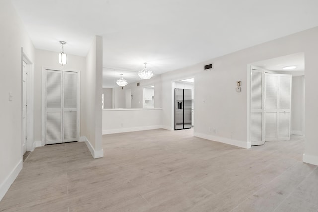 unfurnished living room with a chandelier and light hardwood / wood-style flooring