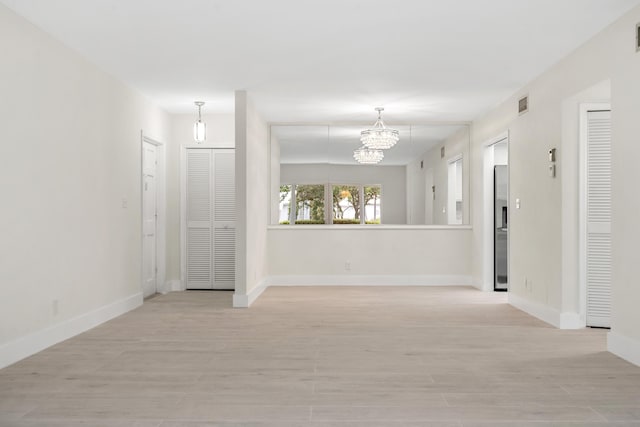 unfurnished room featuring a chandelier and light hardwood / wood-style floors