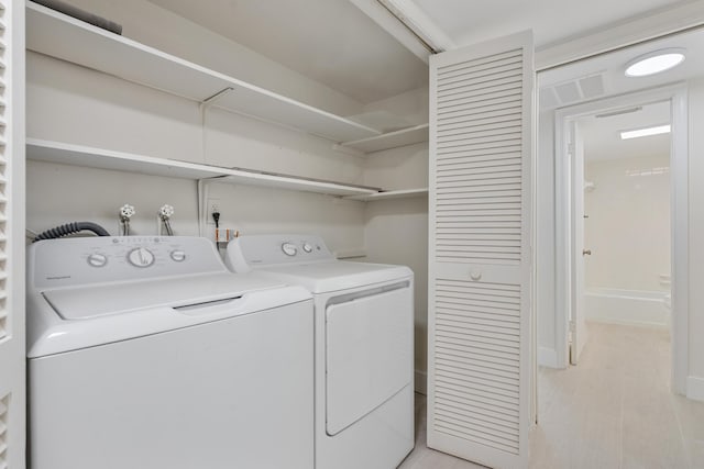 laundry area with separate washer and dryer and light hardwood / wood-style flooring