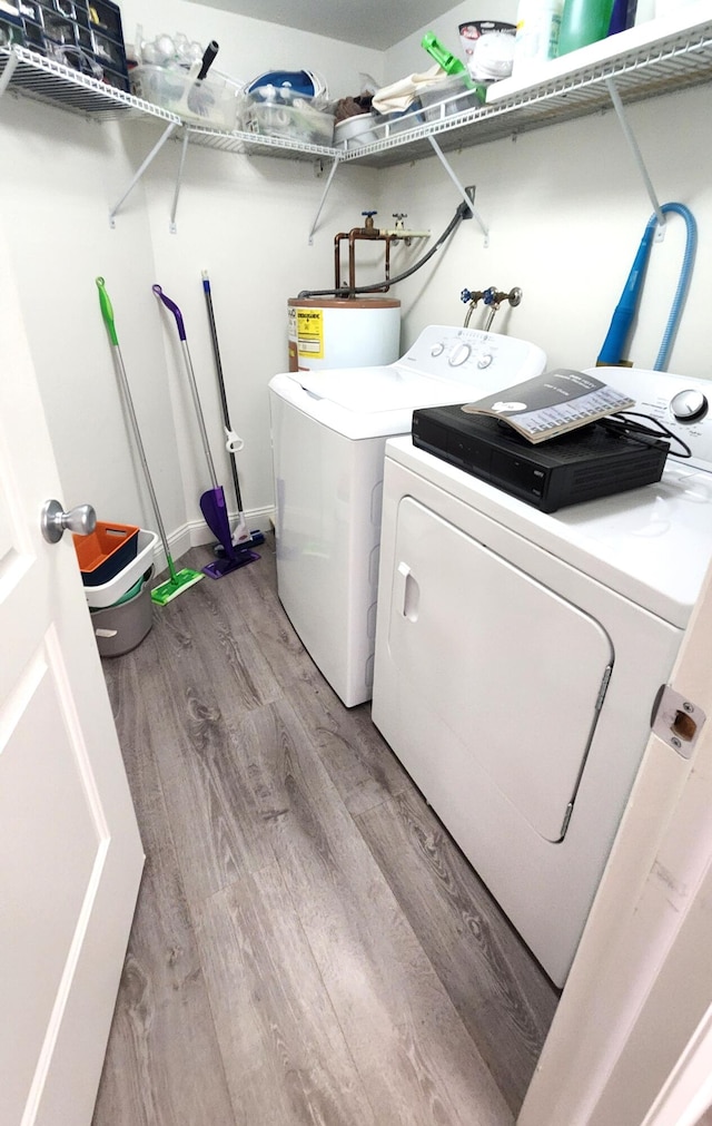 laundry room featuring water heater, light hardwood / wood-style flooring, and washing machine and clothes dryer