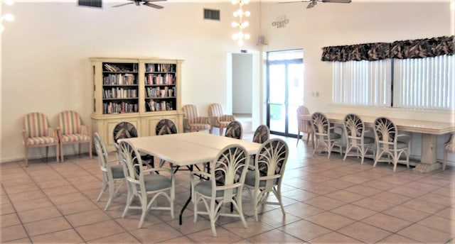 dining room with light tile floors, ceiling fan, and a towering ceiling