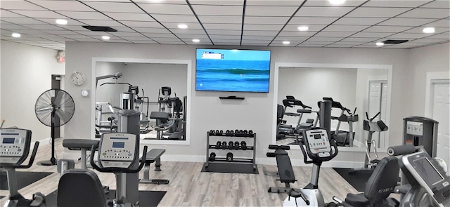 exercise room with a drop ceiling and light wood-type flooring