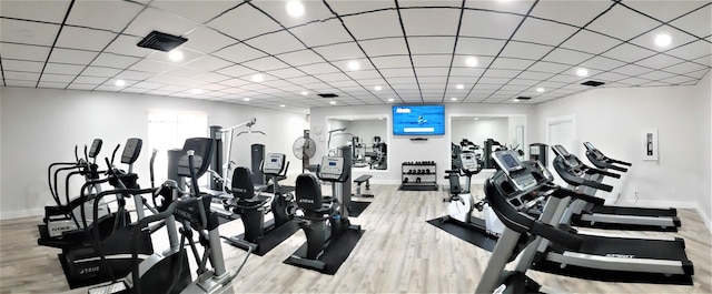 exercise room with a paneled ceiling and light wood-type flooring