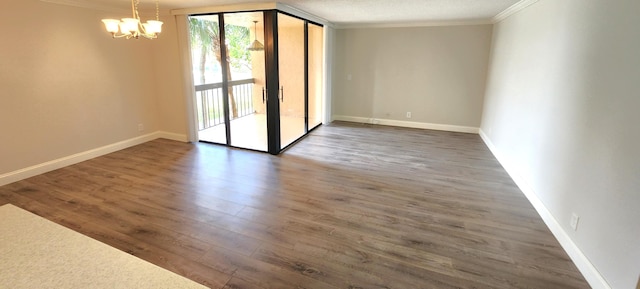 empty room featuring an inviting chandelier, dark hardwood / wood-style flooring, and ornamental molding