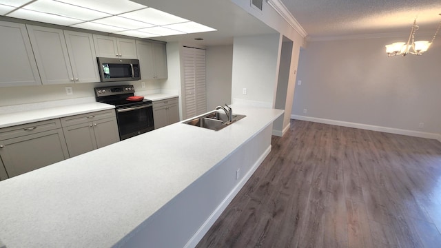 kitchen featuring a notable chandelier, ornamental molding, dark wood-type flooring, appliances with stainless steel finishes, and sink