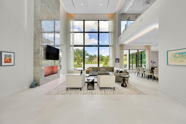 living room with plenty of natural light, a high ceiling, and a tiled fireplace