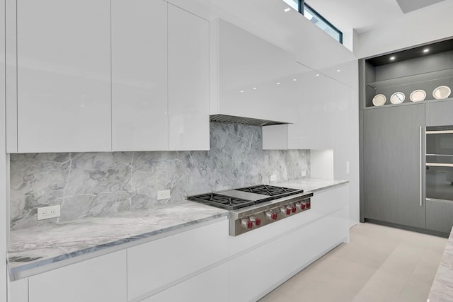 kitchen featuring light stone counters, tasteful backsplash, white cabinetry, stainless steel gas cooktop, and light tile flooring