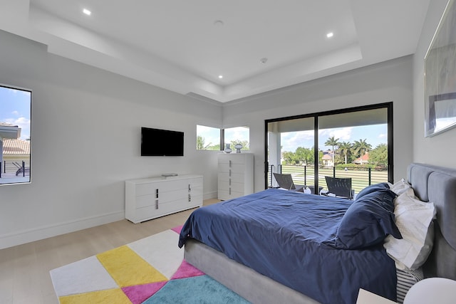 bedroom featuring a tray ceiling and light hardwood / wood-style floors