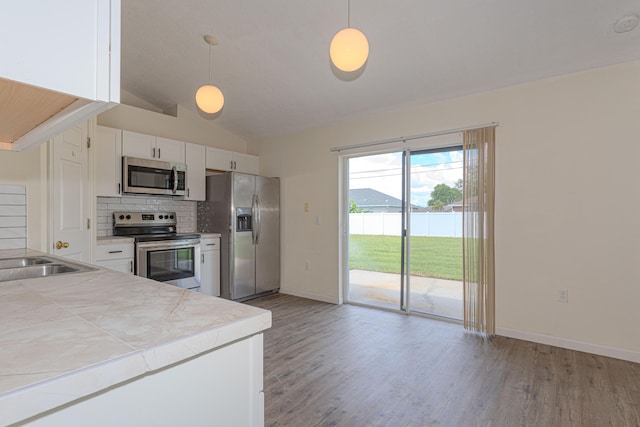 kitchen featuring lofted ceiling, decorative backsplash, light wood-type flooring, and stainless steel appliances