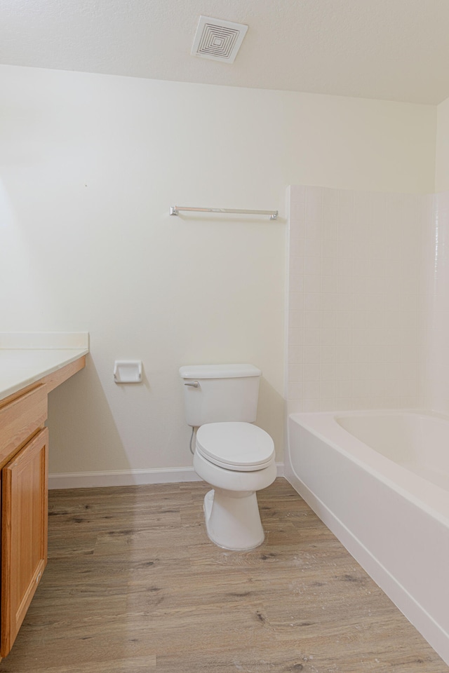 bathroom with hardwood / wood-style floors, an enclosed shower, and toilet