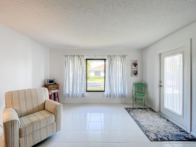 sitting room featuring tile patterned flooring, baseboards, and a textured ceiling