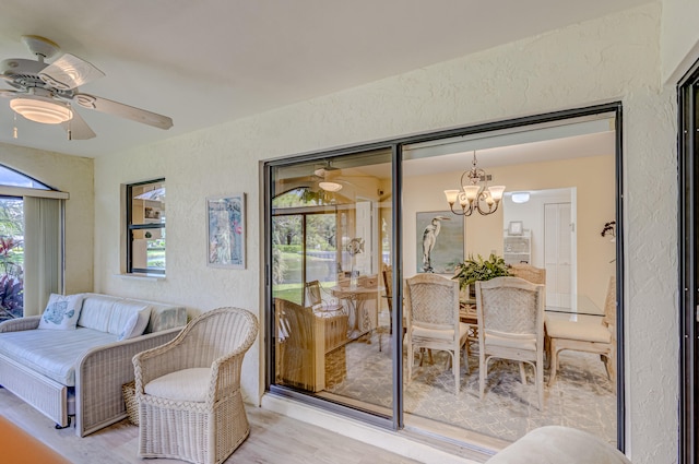 interior space with light wood-type flooring and ceiling fan with notable chandelier