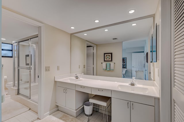 bathroom with an enclosed shower, double sink, tile floors, and vanity with extensive cabinet space