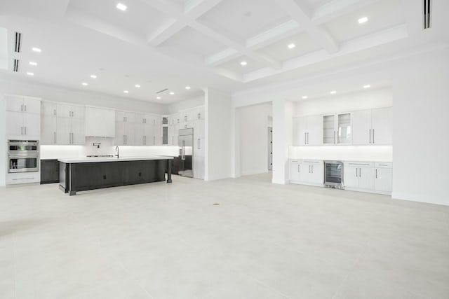 living room featuring beam ceiling, beverage cooler, coffered ceiling, and ornamental molding