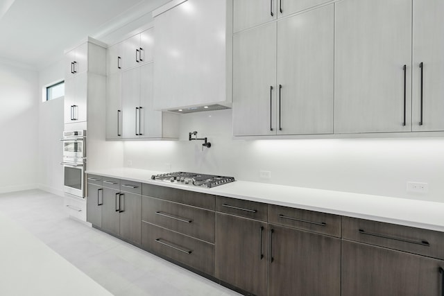 kitchen featuring dark brown cabinets, stainless steel appliances, white cabinetry, and ornamental molding