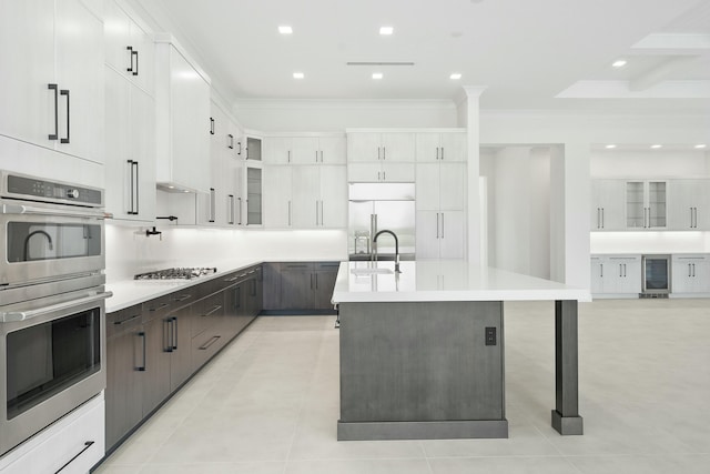 kitchen with a center island with sink, sink, wine cooler, white cabinetry, and stainless steel appliances