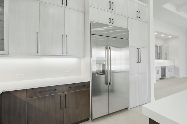 kitchen featuring stainless steel built in refrigerator, dark brown cabinetry, wine cooler, and crown molding