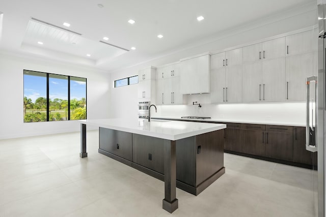 kitchen featuring a kitchen island with sink, a kitchen breakfast bar, sink, dark brown cabinets, and stainless steel appliances