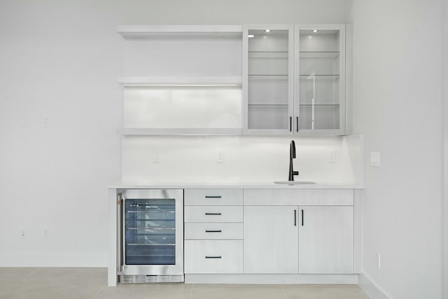 bar featuring light tile patterned floors, beverage cooler, and sink