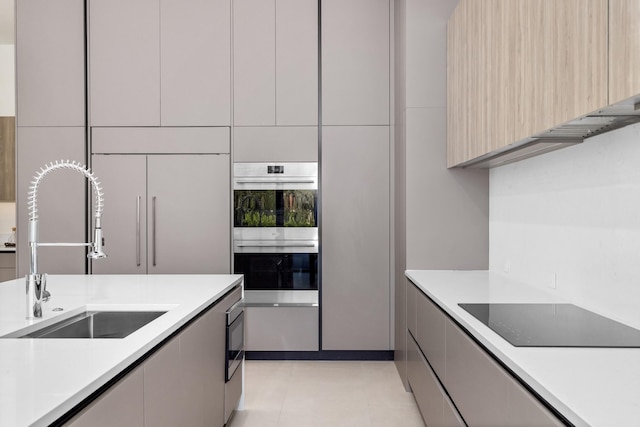 kitchen featuring sink, light brown cabinets, stainless steel double oven, black electric cooktop, and light tile patterned floors