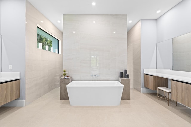 bathroom featuring a bathing tub, vanity, tile walls, and tile patterned flooring