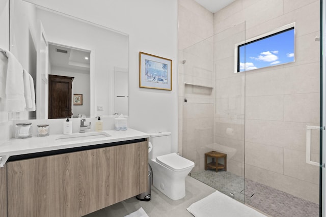 bathroom with vanity, toilet, and tiled shower