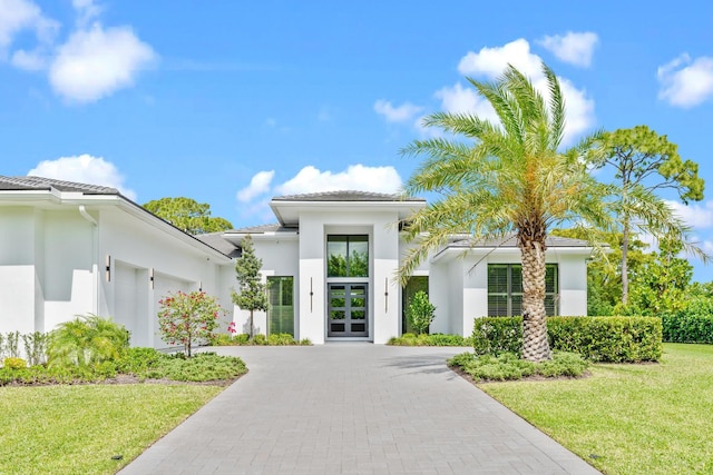 view of front of property featuring a front yard, french doors, and a garage