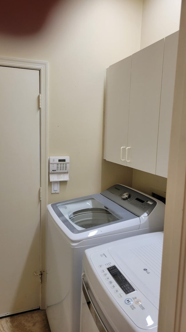 clothes washing area featuring cabinets and washer and clothes dryer