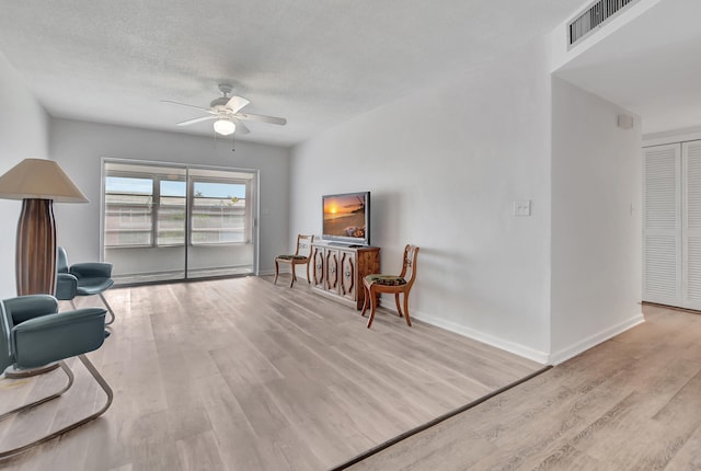 sitting room with ceiling fan, light hardwood / wood-style flooring, and a textured ceiling