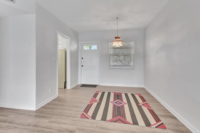 entrance foyer with an inviting chandelier and light hardwood / wood-style floors