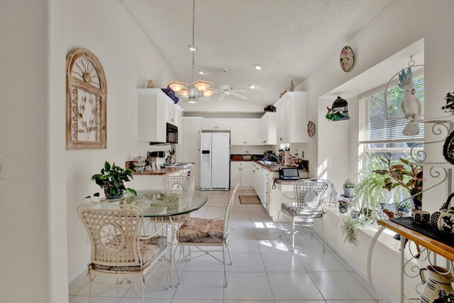 interior space featuring lofted ceiling, hanging light fixtures, ceiling fan with notable chandelier, white appliances, and light tile floors