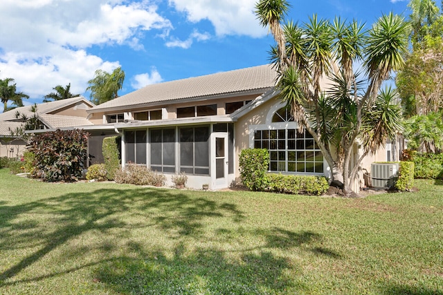 back of property featuring central AC unit, a sunroom, and a lawn