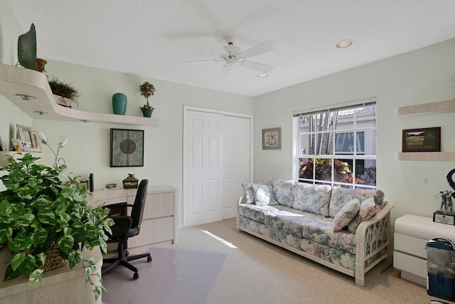 carpeted home office featuring a textured ceiling and ceiling fan