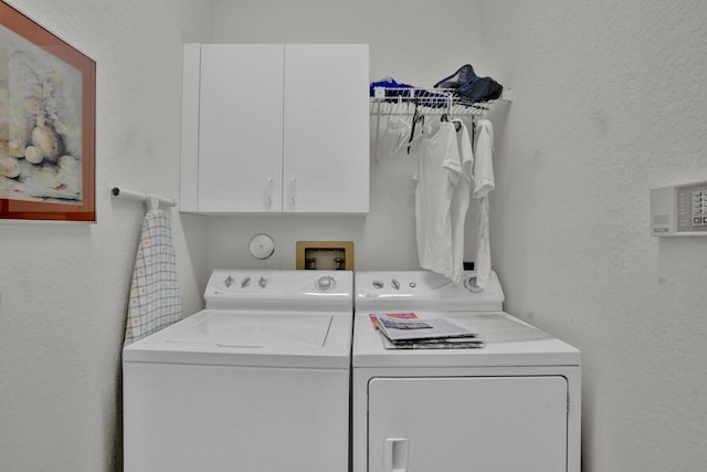 laundry room featuring washer hookup, washing machine and dryer, and cabinets