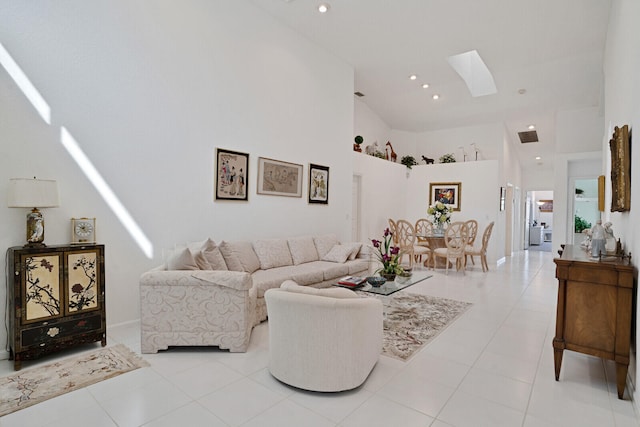 living room with light tile flooring, a skylight, and high vaulted ceiling