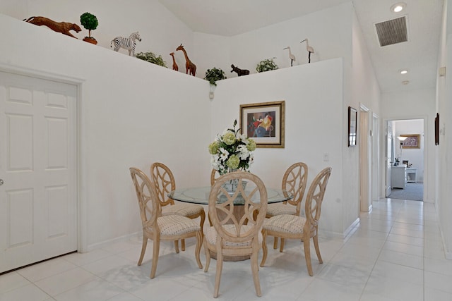 dining room featuring light tile floors and a high ceiling