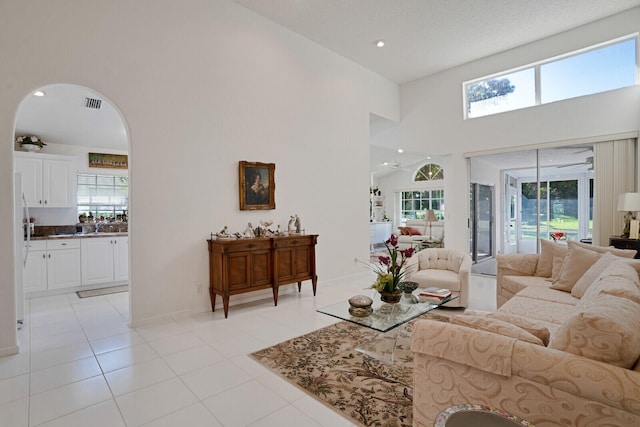 tiled living room featuring plenty of natural light, high vaulted ceiling, and a textured ceiling