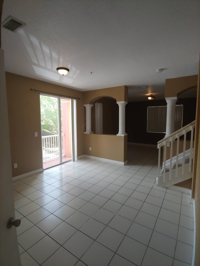 tiled empty room featuring decorative columns