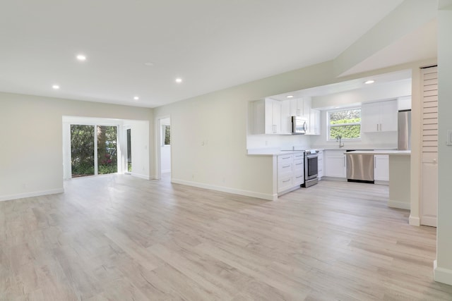 unfurnished living room with light wood-type flooring, recessed lighting, and baseboards