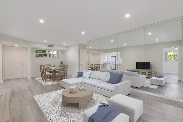 living area featuring light wood-style floors, recessed lighting, visible vents, and baseboards