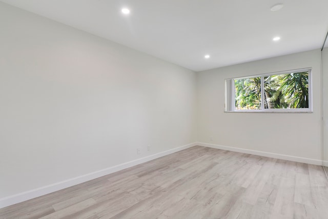 empty room with light wood finished floors, recessed lighting, and baseboards