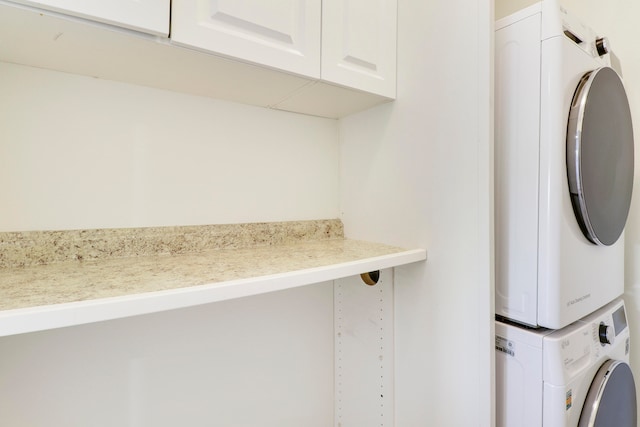 laundry room with cabinet space and stacked washing maching and dryer