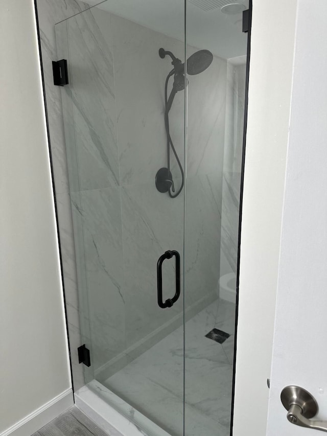 full bathroom featuring a marble finish shower and baseboards