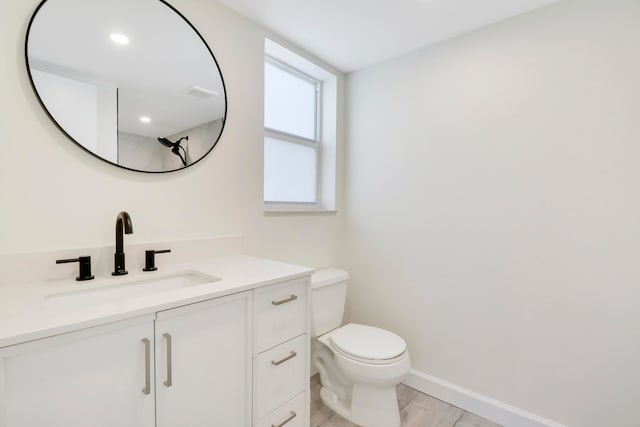 bathroom with baseboards, vanity, and toilet