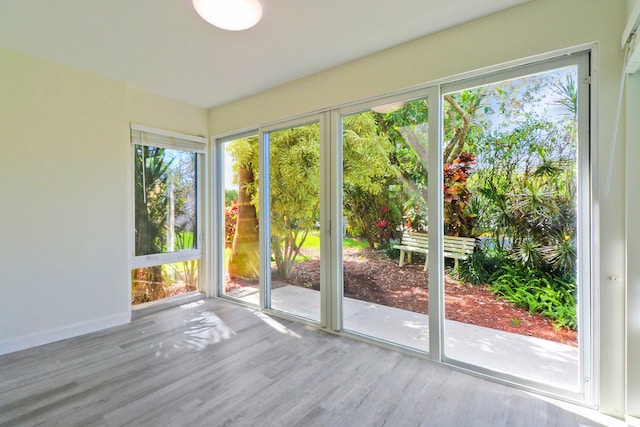 doorway to outside featuring a sunroom, baseboards, and wood finished floors